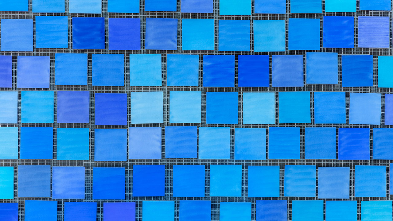 Square water color paintings, each a slightly different shade of blue, hang on a wall in a grid-like pattern.