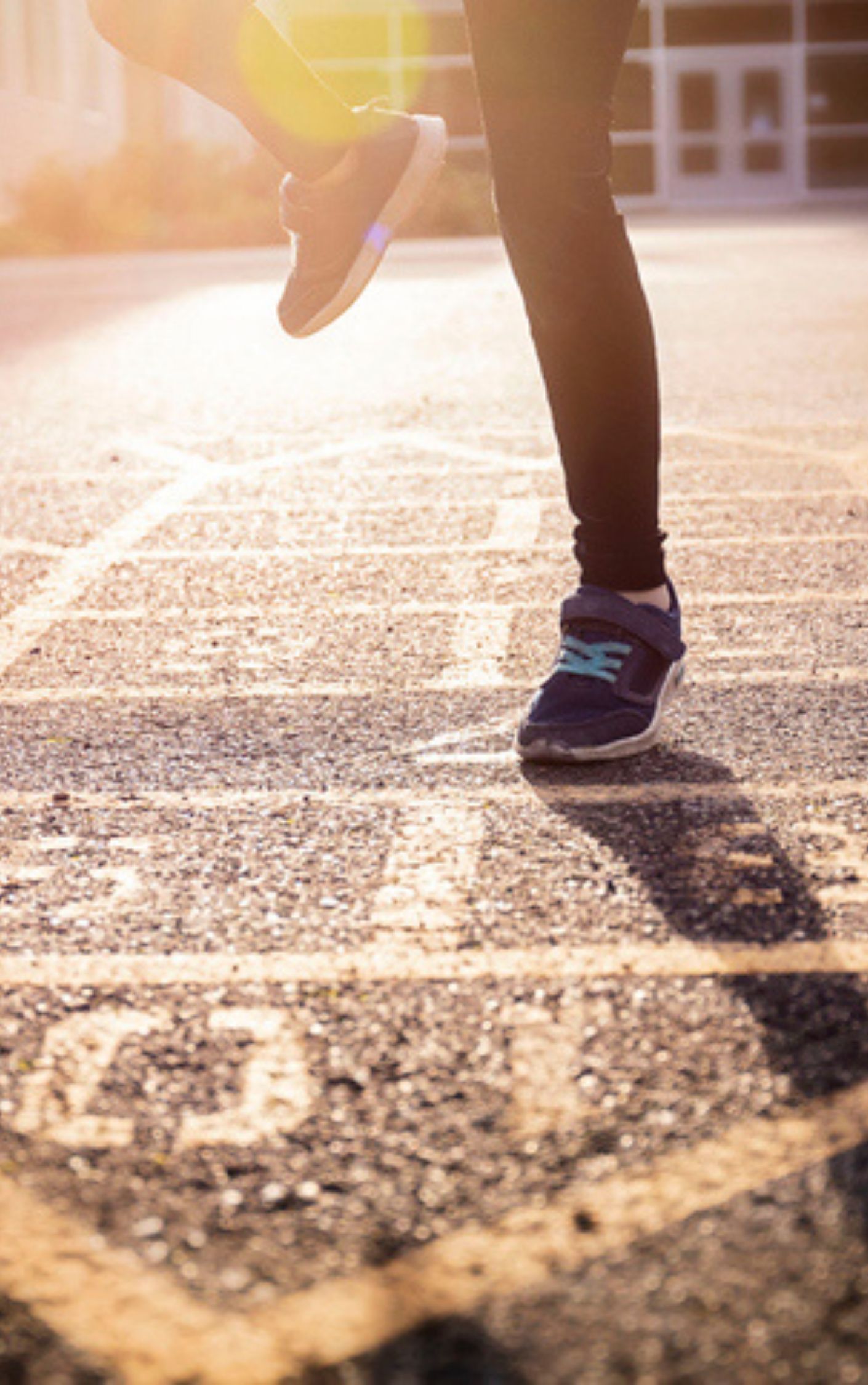 a young girl playing hopscotch on black pavement