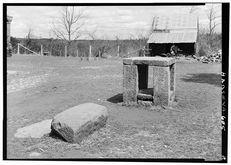 Photographic view of slavery auction block at Green Hill Plantation, showing farm buildings in the background of the auction block.